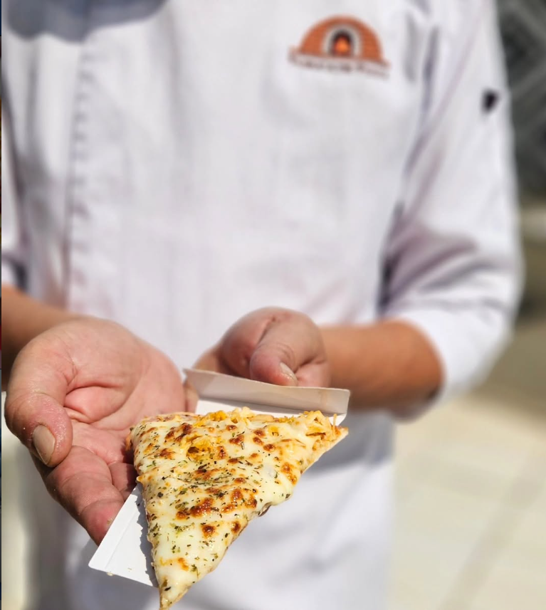 Chef da Fábrica de Pizza oferecendo uma fatia