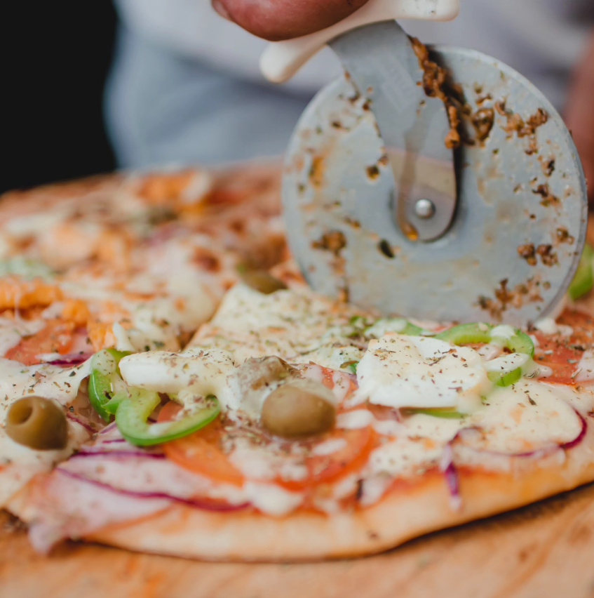 Pizza portuguesa sendo cortada na tábua
